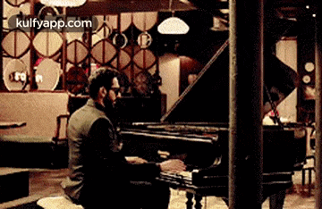 a man is sitting on the floor playing a piano in a restaurant .