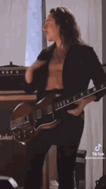 a man is playing a guitar without a shirt on .