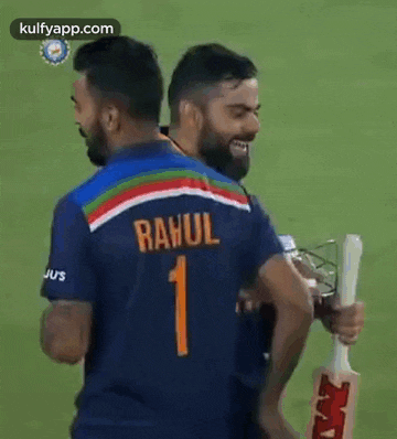 a man with a beard is shaking hands with another man on a cricket field .
