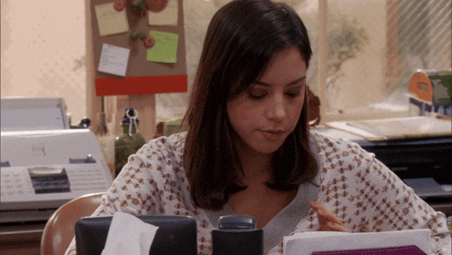 a woman sits at a desk in front of a printer with a sticker that says ' a ' on it