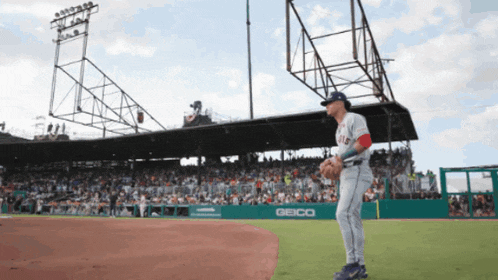 a baseball player stands on a field with a geico sign