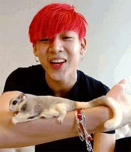 a man with red hair is holding a sugar glider in his arms .
