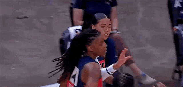 a basketball player is giving a high five to another player while sitting on the court .