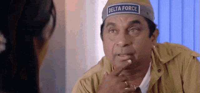 a man wearing a hat with the word delta force on it is talking to a woman .