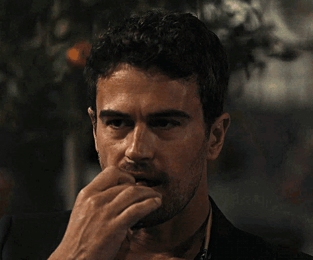 a man with a beard is smoking a cigar with his finger in his mouth