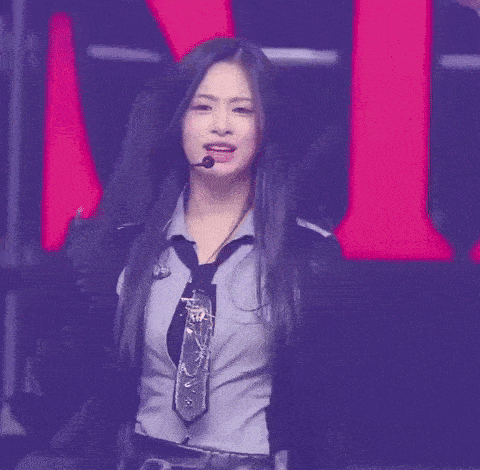 a woman wearing a tie and a microphone is dancing on a stage