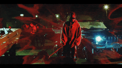 a man in a red hoodie stands in front of a jeep with a license plate that starts with the letter c