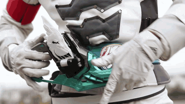 a person wearing a white suit and gloves is holding a green object that says ' a ' on it