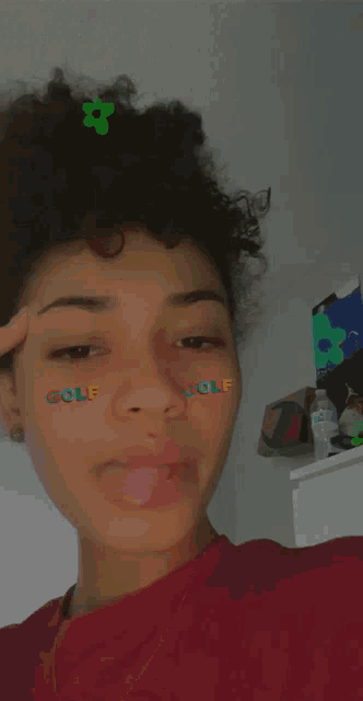 a girl with curly hair is sticking her tongue out and has golf stickers on her face .