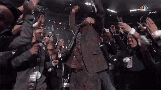 a man in a sweatshirt that says nbc on it is dancing in front of a crowd