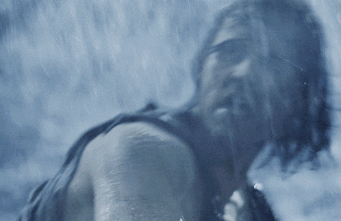 a man with a beard is standing in the rain looking at the camera