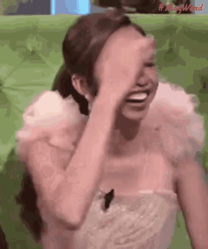 a woman in a white dress is covering her face with her hand while laughing .