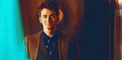 a man in a suit and tie is standing in front of a door in a dark room .