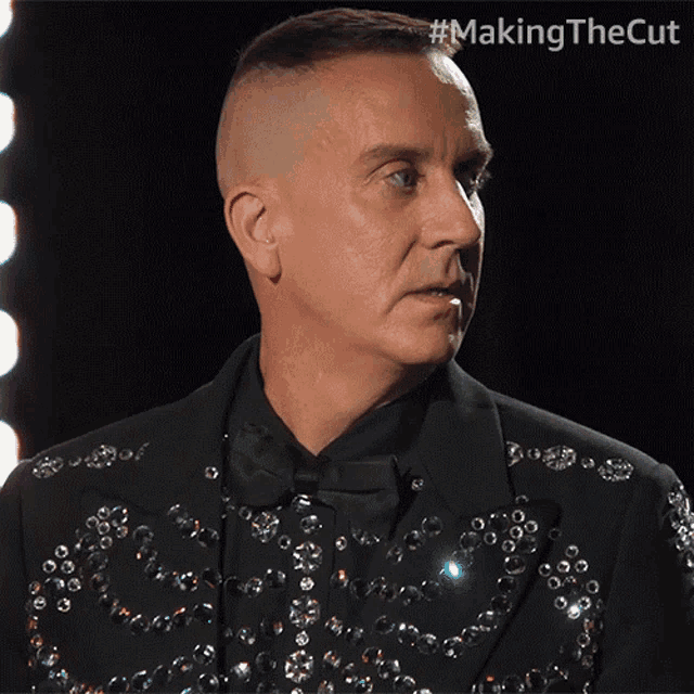 a man is wearing a black suit with sequins on it and the words making the cut below him