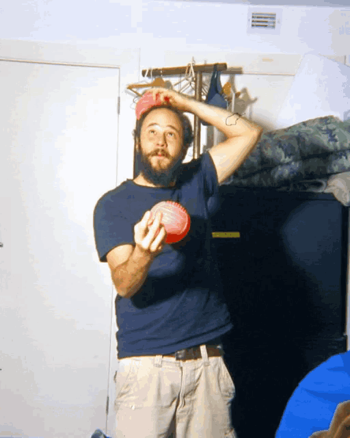 a man with a beard is holding a red ball in his hand