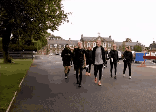 a group of people are walking down a road in front of a building