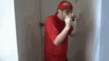 a man wearing a red shirt and a red hat is standing in a room .