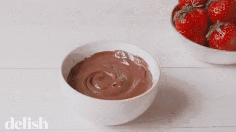 a bowl of chocolate next to a bowl of strawberries with the word delish on the bottom