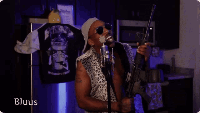 a man is singing into a microphone while holding a gun and the word bluus is visible in the corner