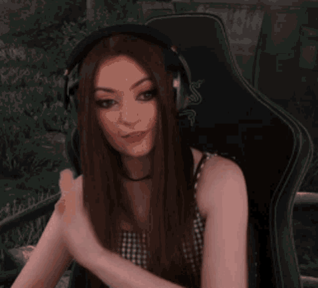 a woman wearing headphones is sitting in a chair and covering her face