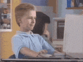 a boy in a blue shirt is typing on a keyboard