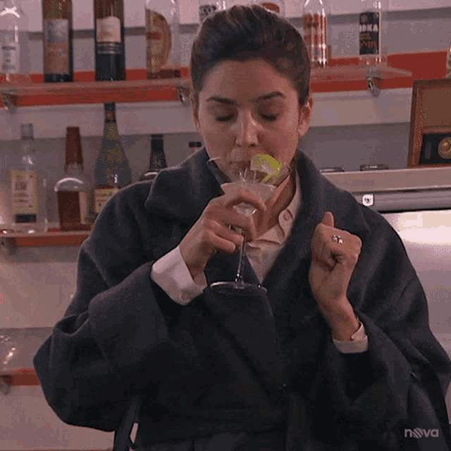 a woman drinking from a martini glass with nova written on the bottom