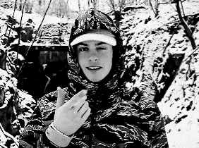 a black and white photo of a young man wearing a hooded jacket and a hat .