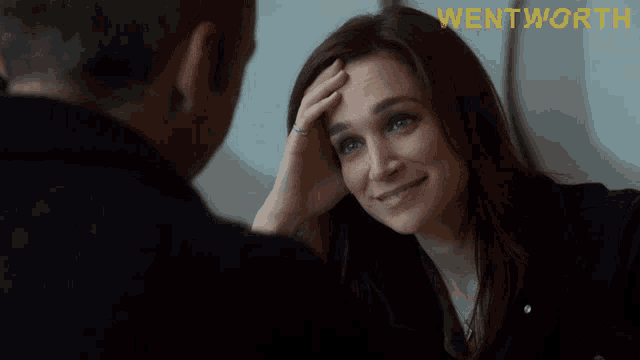 a woman is smiling while looking at a man with the word wentworth on the bottom right