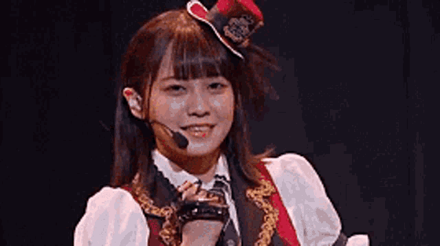 a young woman wearing a hat and a microphone is smiling on a stage .
