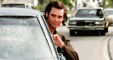 a man is sticking his head out of a car window on a street .