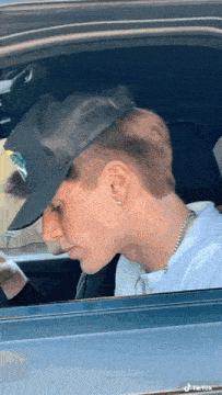 a man wearing a hat is sitting in a car with tiktok written on the bottom