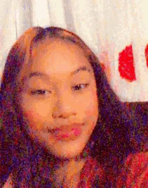 a close up of a girl 's face with a blurry background and a red heart in the background .