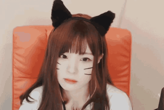 a girl wearing a cat ear headband is sitting in an orange chair