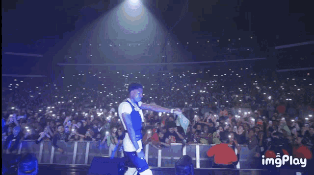 a man stands on a stage with a crowd behind him and the words imgplay on the bottom