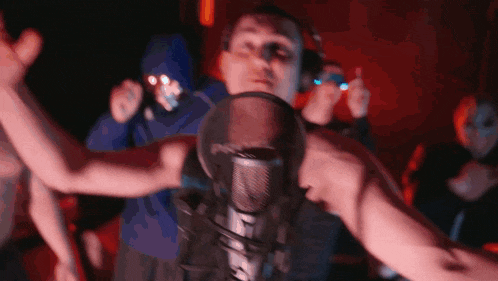 a group of people are dancing in front of a microphone in a dark room