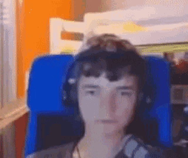 a young boy wearing headphones is sitting in a blue chair in front of a computer .