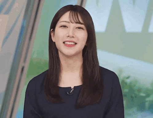 a woman with long hair is smiling and wearing a blue shirt