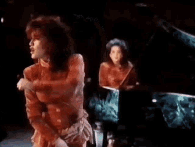 a woman in a red dress is pointing at the camera with her hand .