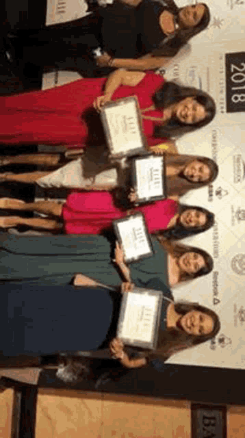 a group of women are posing for a picture while holding plaques