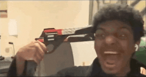 a man is holding a toy gun in front of his face .
