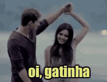 a man and a woman are dancing on the beach with the words oi , gatinha above them