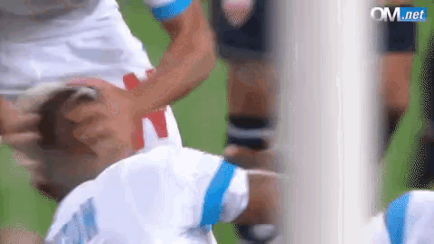 a soccer player is being tackled by another player during a game on a field .