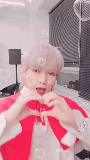 a man is making a heart shape with his hands while wearing a santa hat .