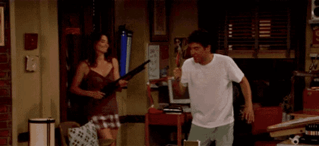 a man and a woman are standing in a room and the woman is holding a sword .