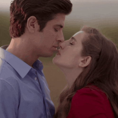 a man and a woman are kissing and the woman is wearing a red top