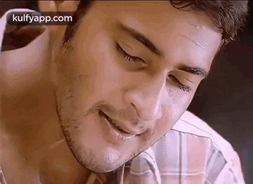 a close up of a man 's face with his eyes closed and a scratch on his forehead .