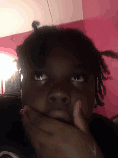 a young girl covering her mouth with her hand and looking up