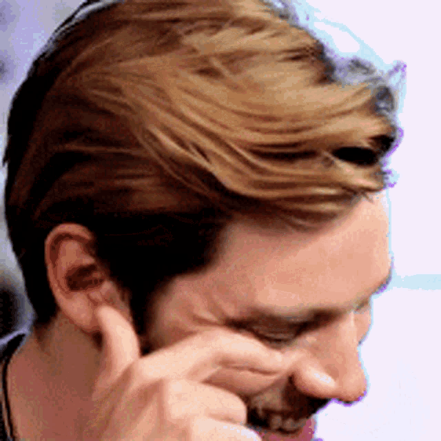 a man with a beard is touching his nose with his finger