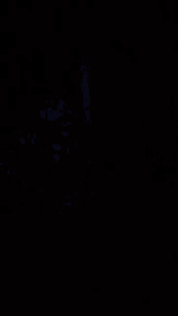a man wearing glasses and a hat is looking at the camera in the dark