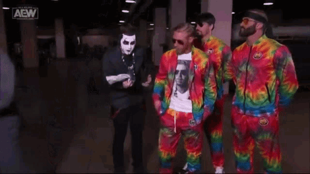 three men in tie dye jackets are giving each other a high five
